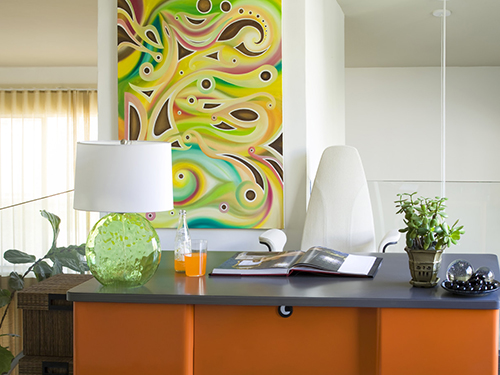 whimsical fun in this modern styled home office.a reclaimed metal desk from the 50's was repainted in this vibrant orange.other vibrant colors of lime in the glass desk lamp and multi colors in the original artwork give a sense of energy to the room.